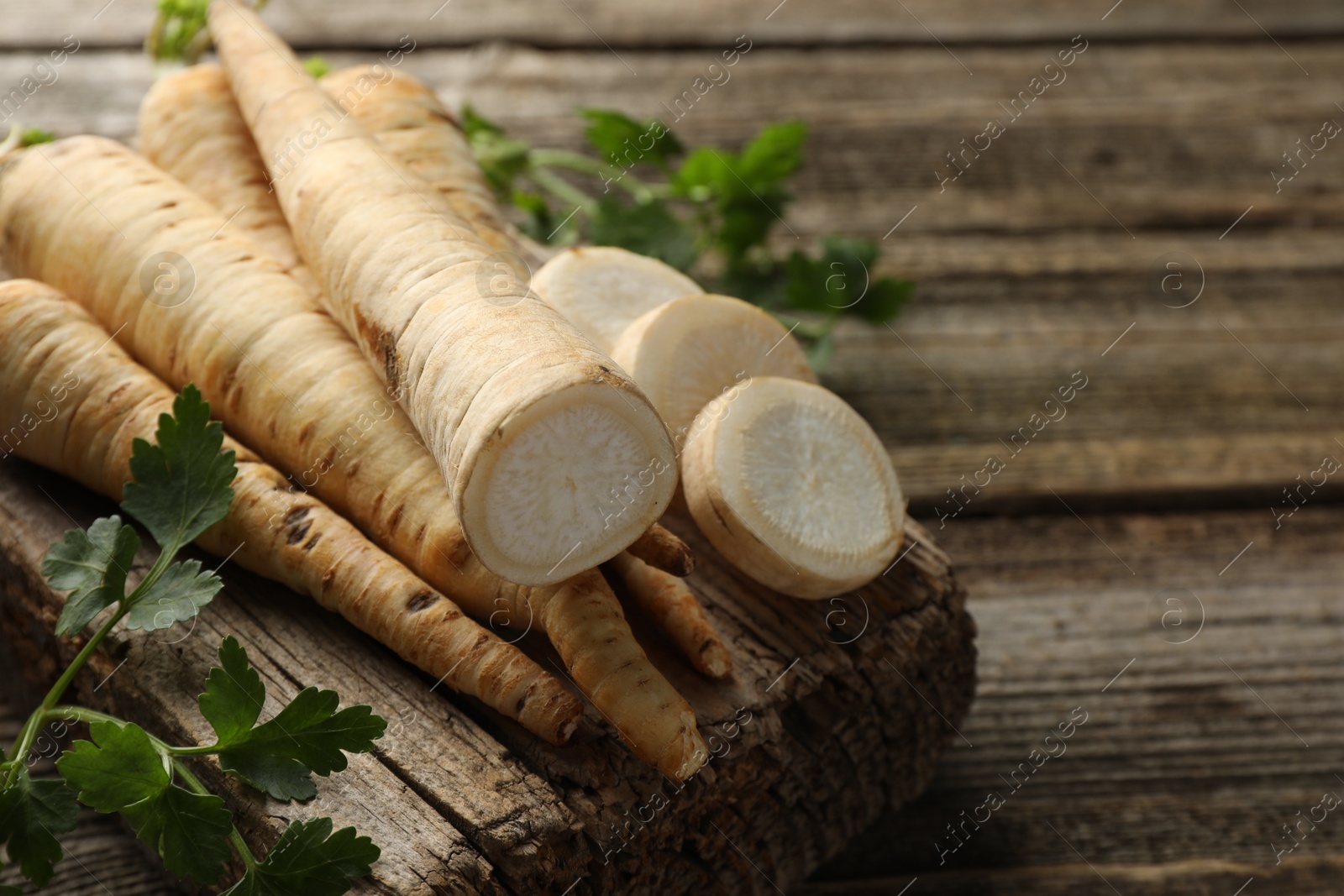 Photo of Parsley roots and leaves on wooden table, closeup. Space for text