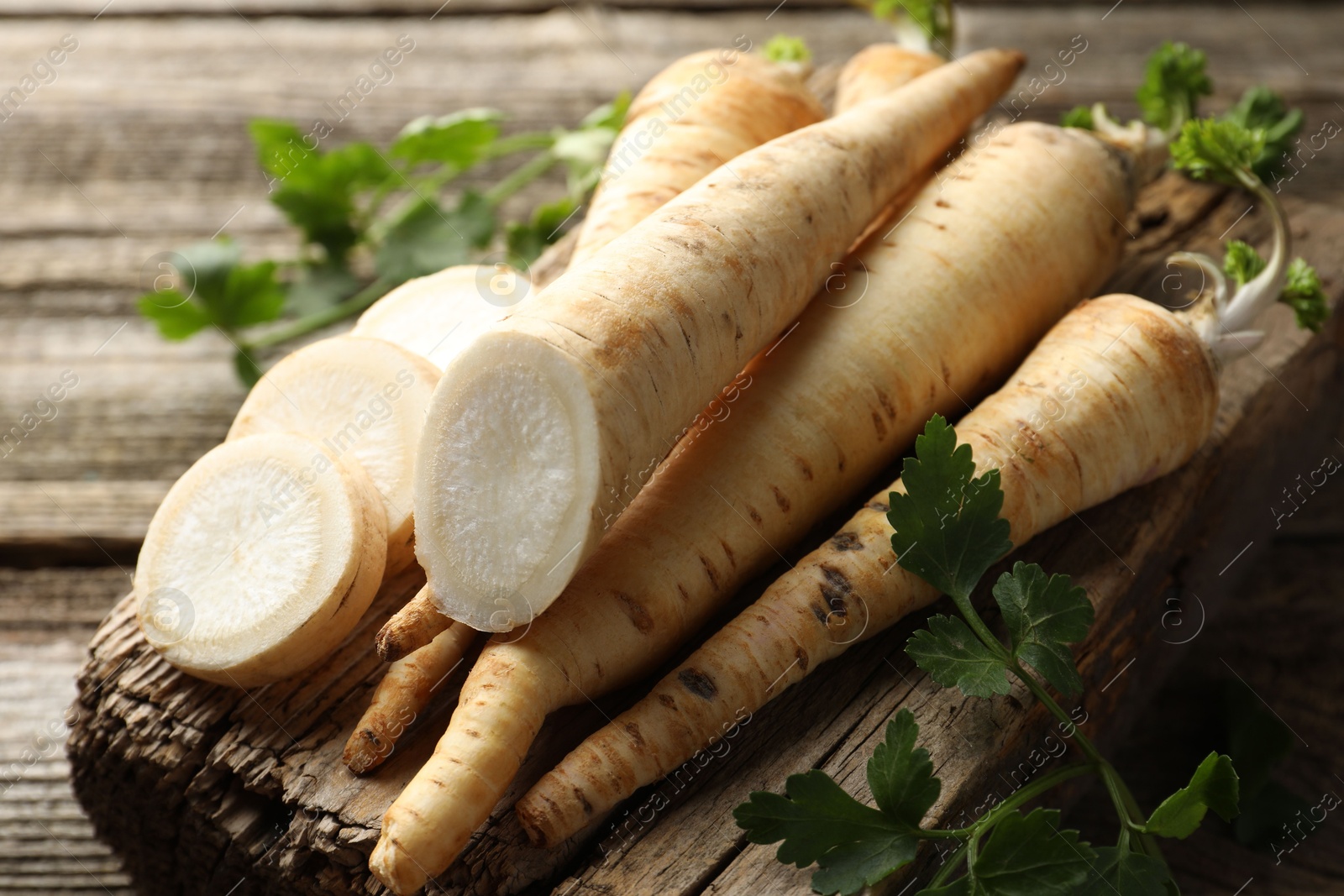 Photo of Parsley roots and leaves on wooden table, closeup