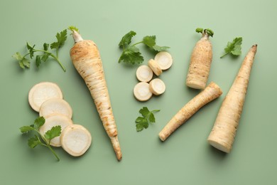 Photo of Parsley roots and leaves on green background, flat lay