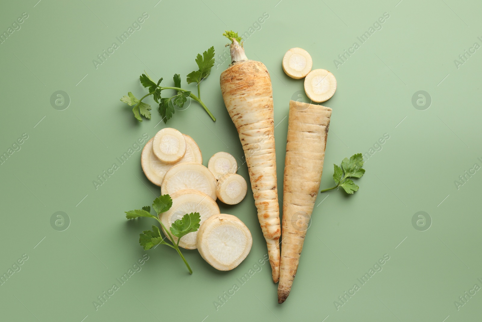 Photo of Parsley roots and leaves on green background, flat lay