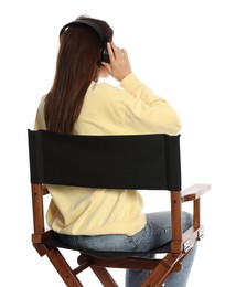 Photo of Woman with headset sitting in director's chair on white background, back view