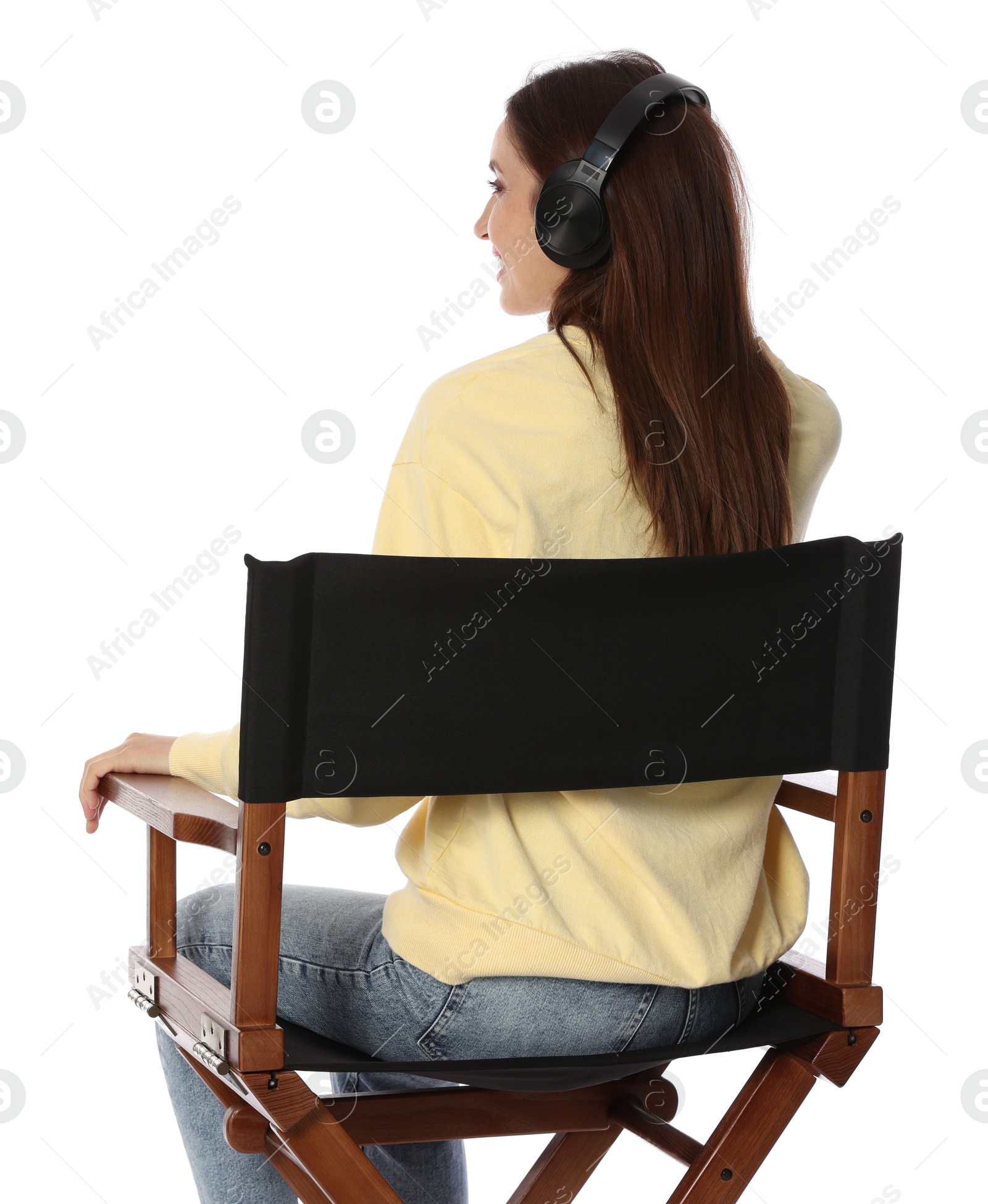 Photo of Woman with headset sitting in director's chair on white background, back view