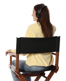 Photo of Woman with headset sitting in director's chair on white background, back view