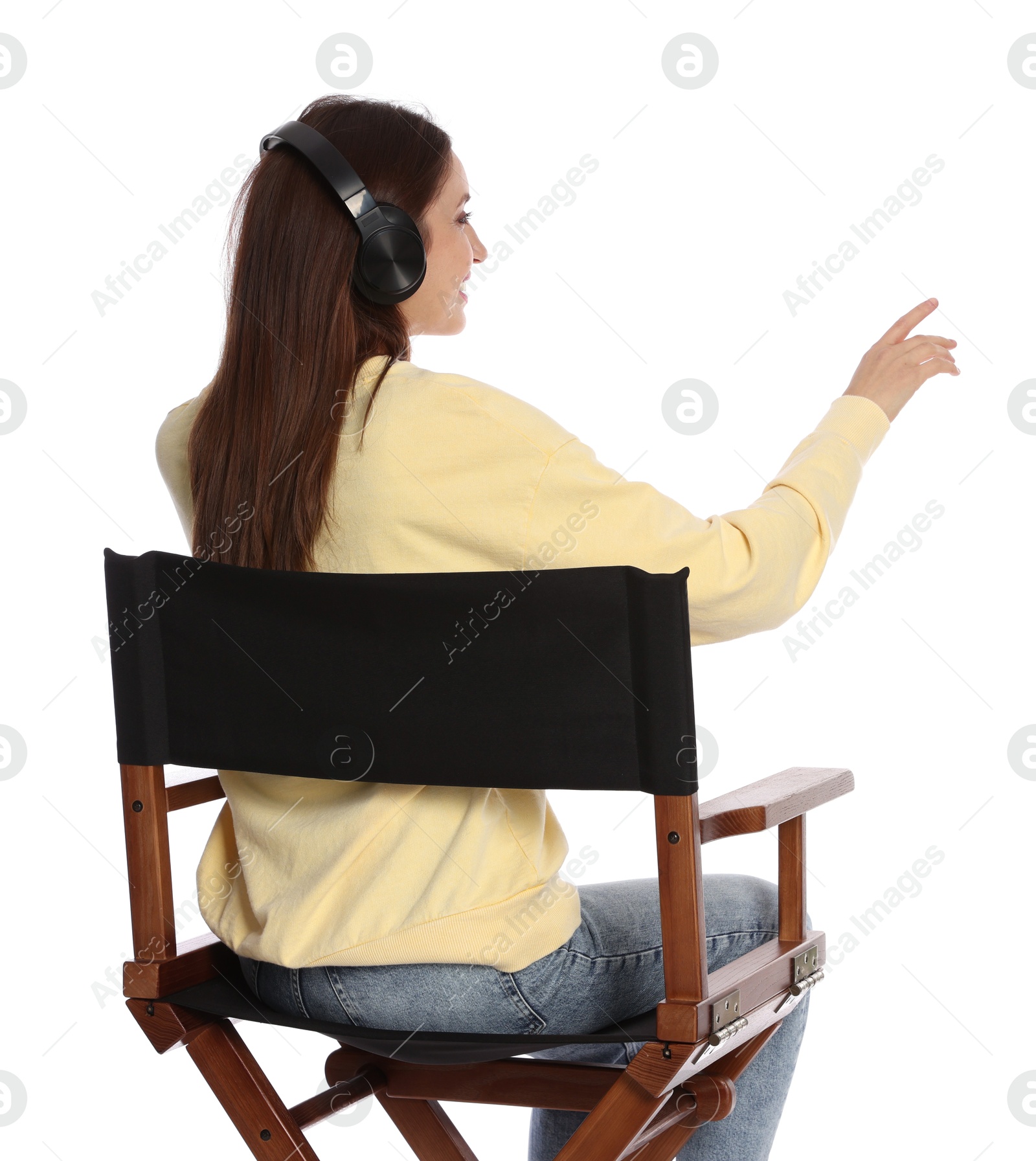 Photo of Woman with headset sitting in director's chair on white background, back view