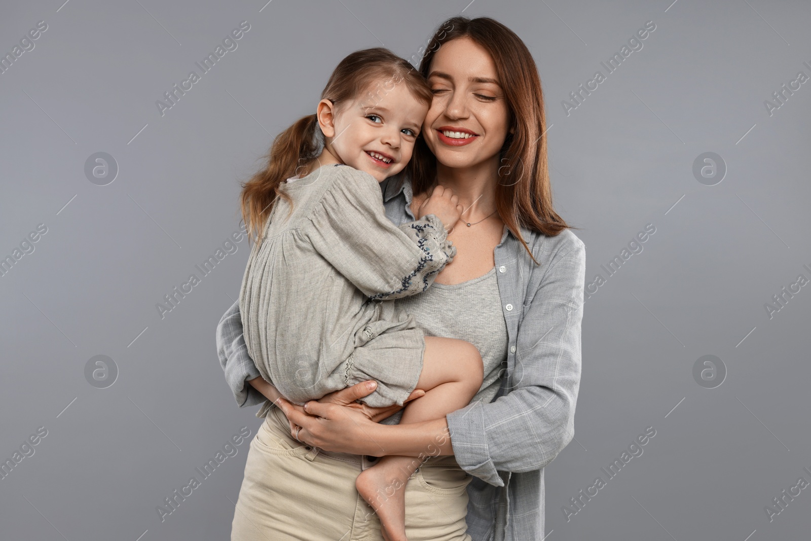 Photo of Happy mother with her cute little daughter on grey background