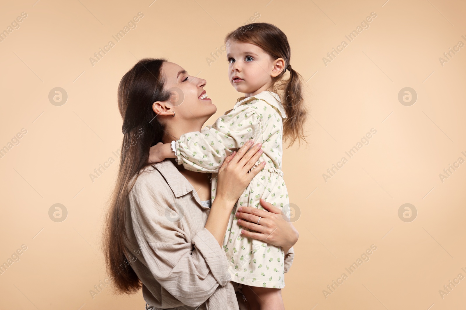 Photo of Happy mother with her cute little daughter on beige background