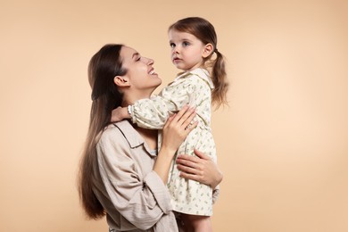 Photo of Happy mother with her cute little daughter on beige background