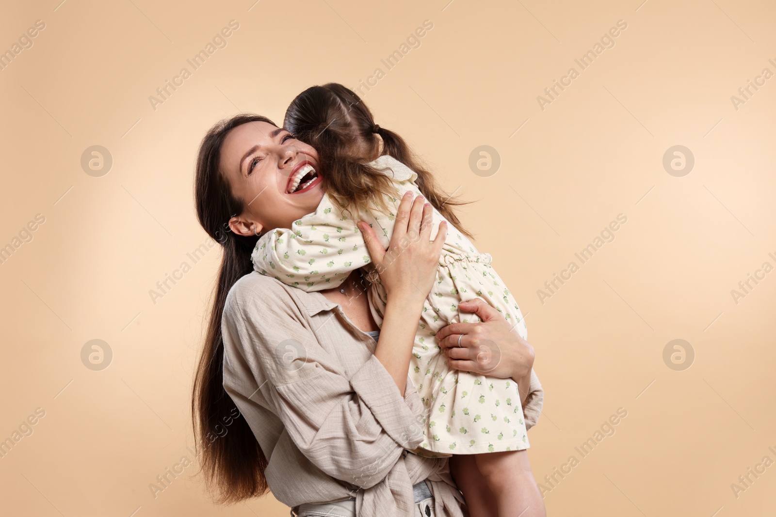 Photo of Happy mother with her cute little daughter on beige background