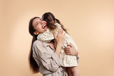 Happy mother with her cute little daughter on beige background