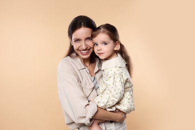 Photo of Portrait of happy mother with her cute little daughter on beige background