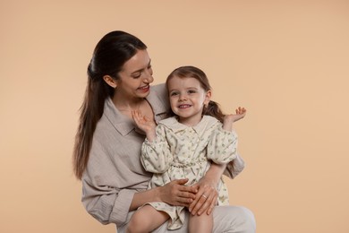 Photo of Happy mother with her cute little daughter on beige background