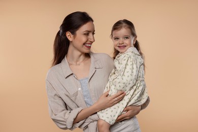 Happy mother with her cute little daughter on beige background