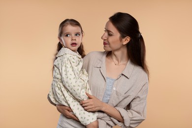 Photo of Beautiful mother with her cute little daughter on beige background