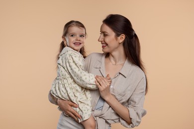 Happy mother with her cute little daughter on beige background