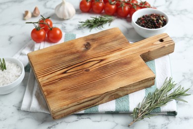 Photo of Wooden cutting board and different products on white marble