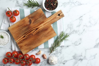 Photo of Wooden cutting board and different products on white marble, flat lay. Space for text