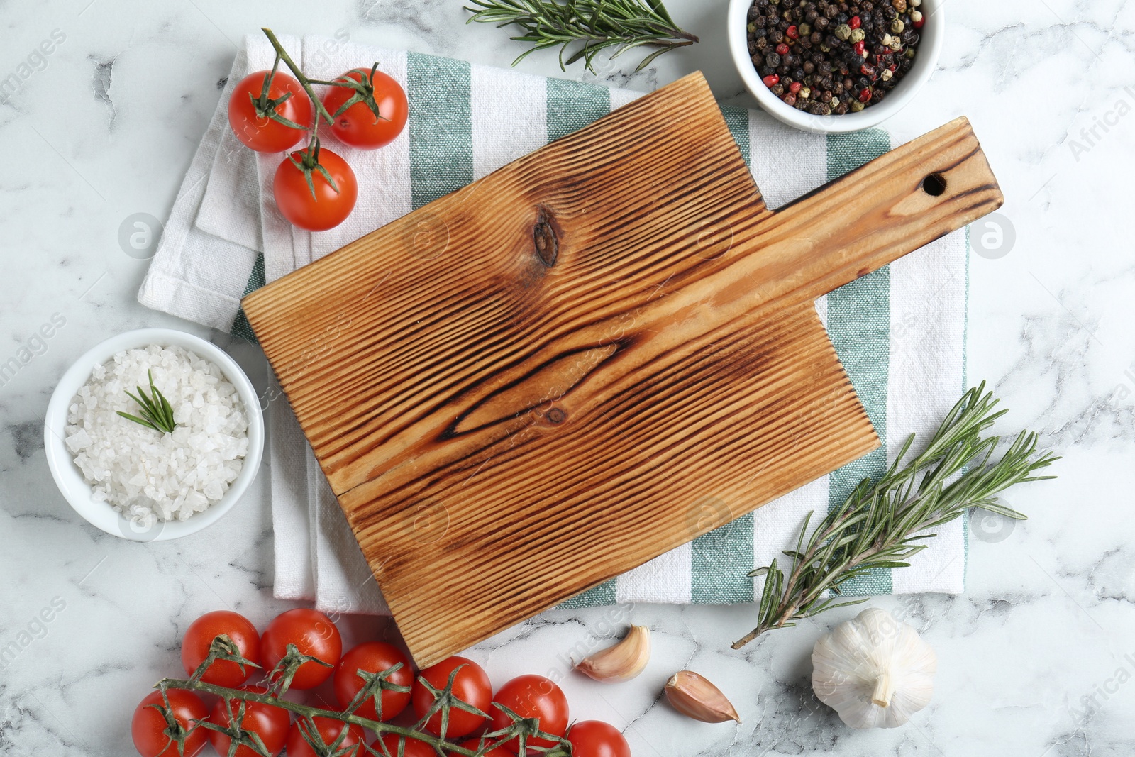 Photo of Wooden cutting board and different products on white marble, flat lay. Space for text