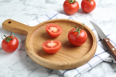 Photo of Wooden cutting board, tomatoes and knife on white marble table