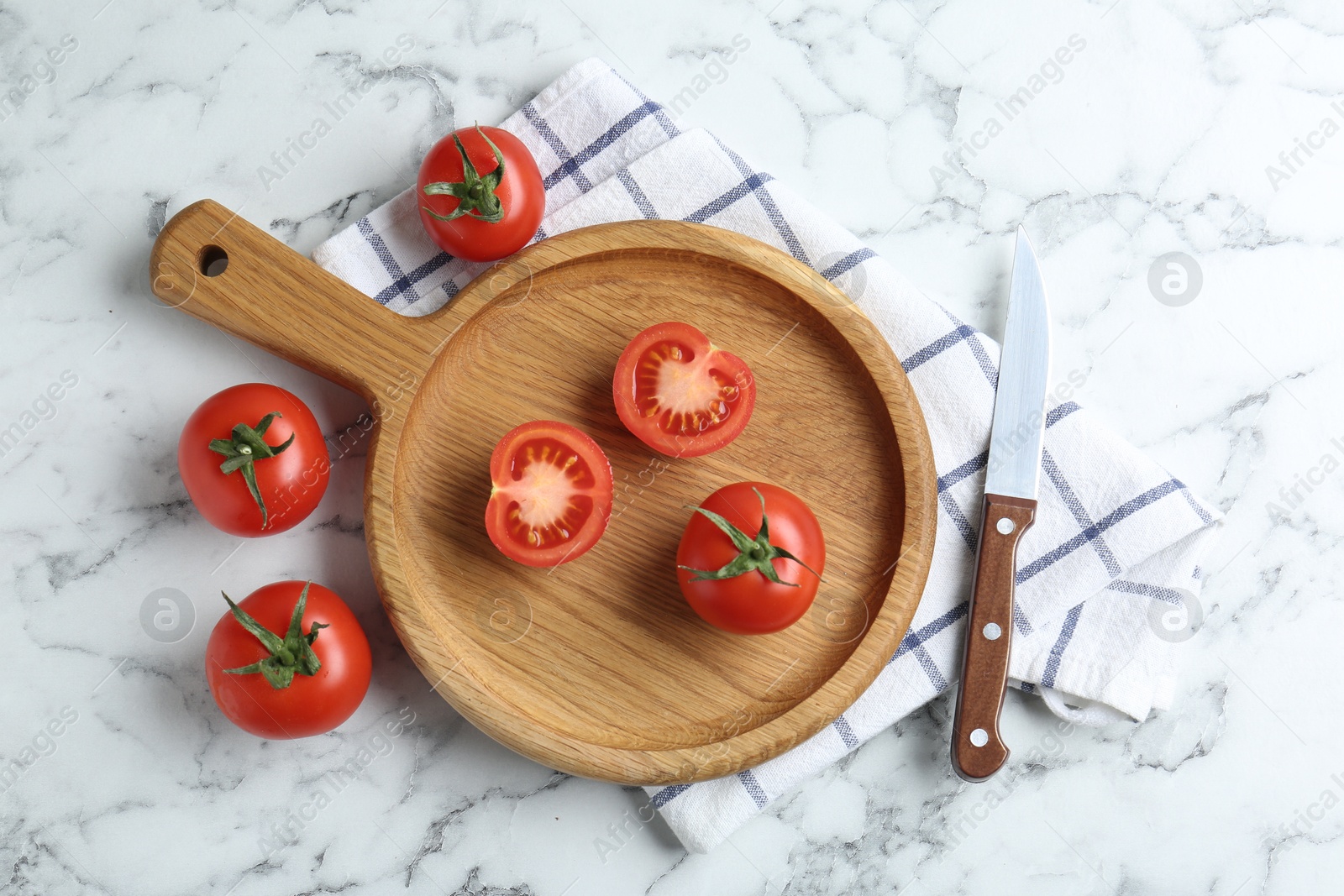 Photo of Wooden cutting board, tomatoes and knife on white marble table, flat lay