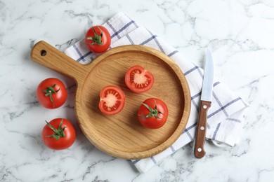 Photo of Wooden cutting board, tomatoes and knife on white marble table, flat lay