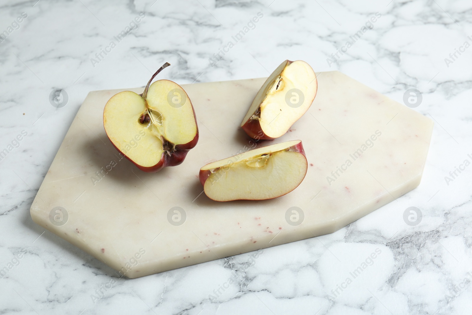 Photo of Cutting board and cut apples on white marble table