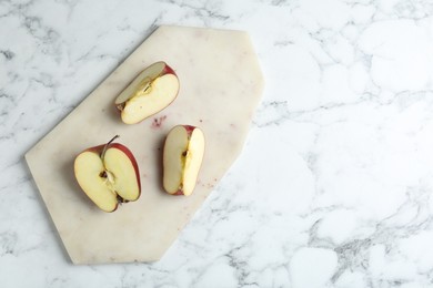 Photo of Cutting board and cut apples on white marble table, top view. Space for text