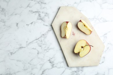 Photo of Cutting board and cut apples on white marble table, top view. Space for text