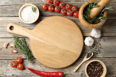 Photo of Cutting board and different products on wooden table, flat lay. Space for text