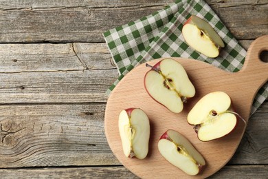 Photo of Cutting board and cut apples on wooden table, top view. Space for text