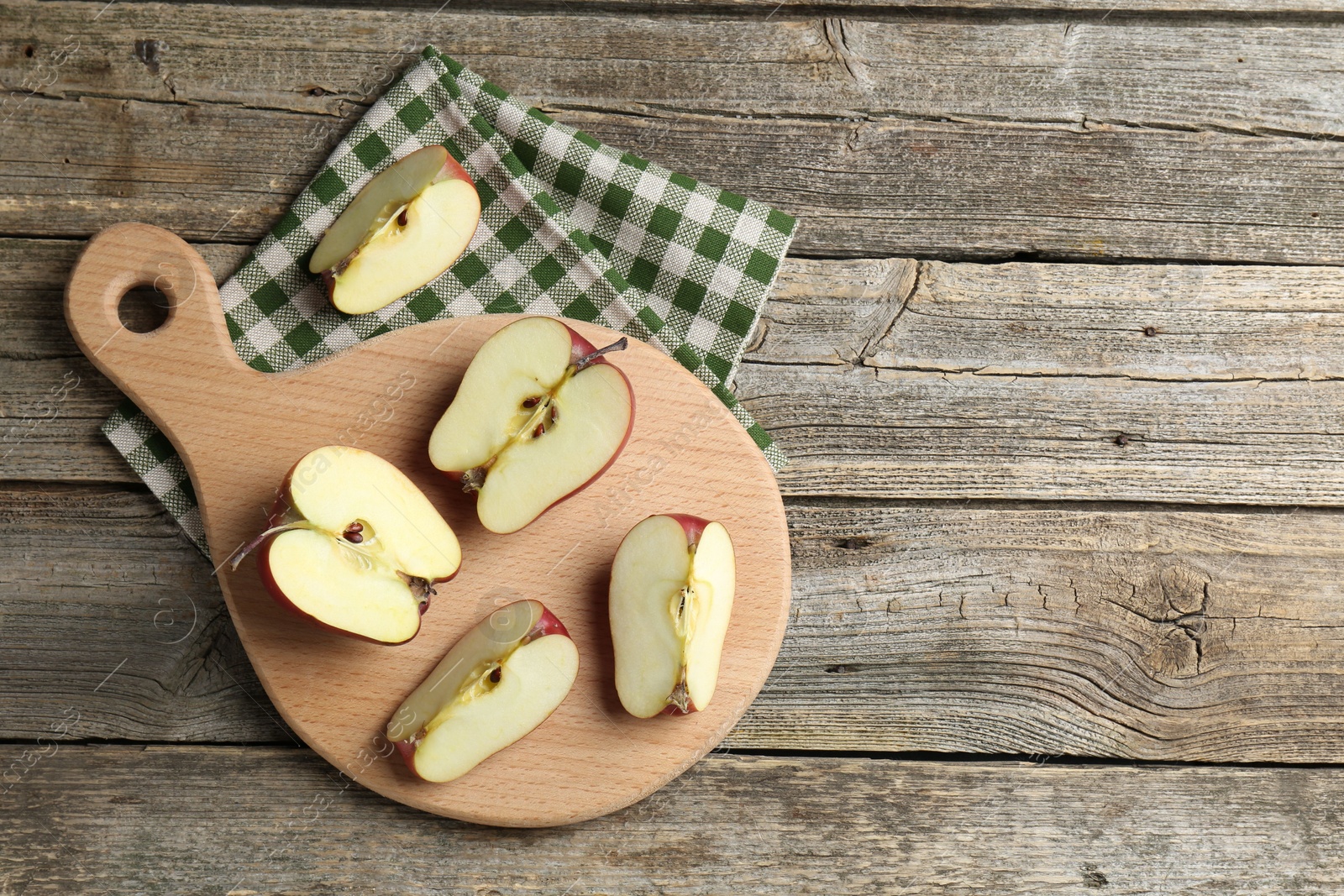 Photo of Cutting board and cut apples on wooden table, top view. Space for text