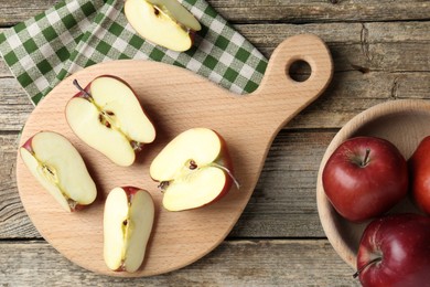 Photo of Cutting board and cut apples on wooden table, flat lay