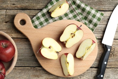 Photo of Cutting board, cut apples and knife on wooden table, flat lay