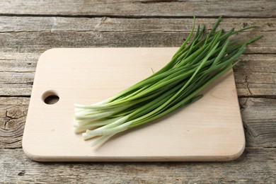 Photo of Cutting board and green onions on wooden table