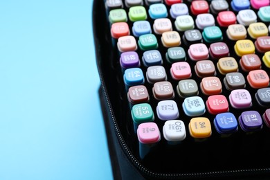 Photo of Many colorful markers in bag on light blue background, closeup. Space for text