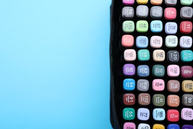 Photo of Many colorful markers in bag on light blue background, top view. Space for text