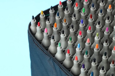 Photo of Many colorful markers in bag on light blue background, closeup