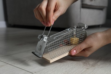 Photo of Woman with metal mouse trap indoors, closeup