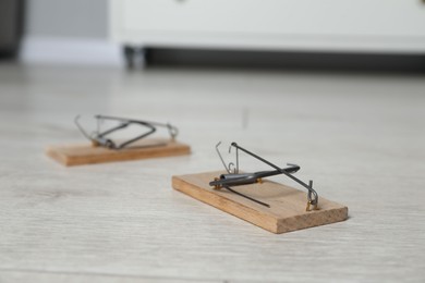 Photo of Spring-loaded bar mousetraps on floor indoors, selective focus