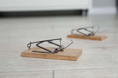 Photo of Spring-loaded bar mousetraps on floor indoors, selective focus