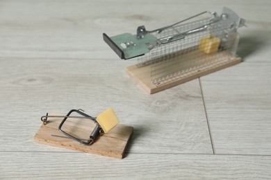 Photo of Two different mouse traps with bait on floor, closeup