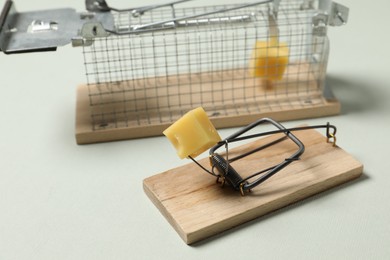 Photo of Two different mouse traps with bait on light background, closeup