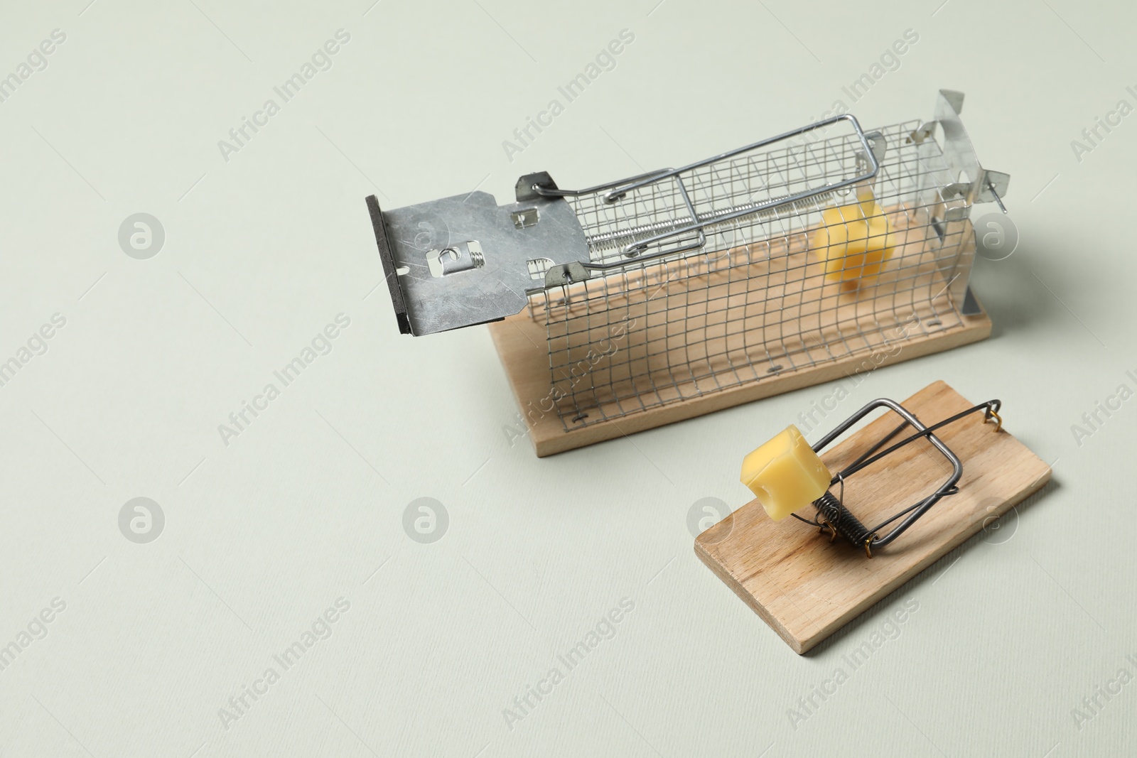 Photo of Two different mouse traps with bait on light background, space for text