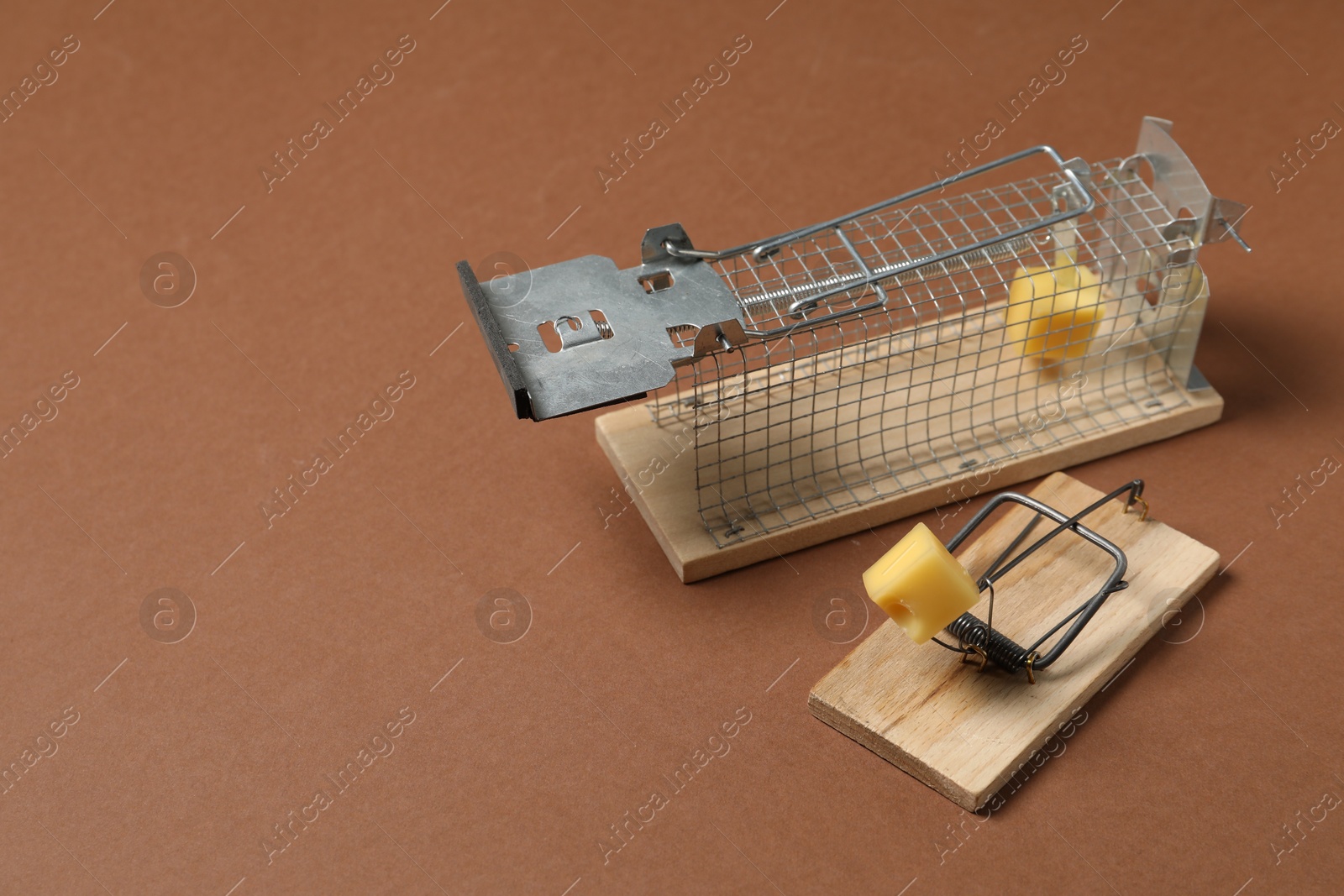 Photo of Two different mouse traps with bait on brown background, space for text