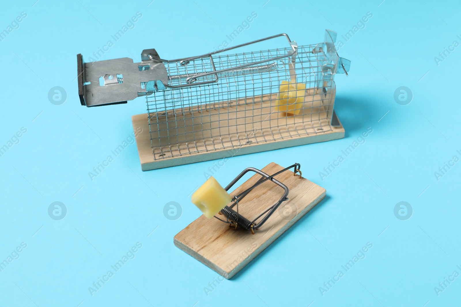 Photo of Two different mouse traps with bait on light blue background