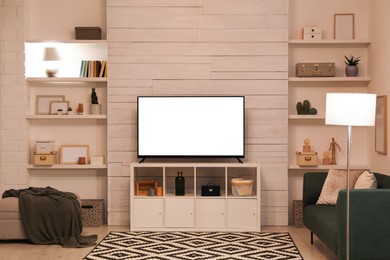 Image of Tv set with white screen on stand in room. Mockup for design