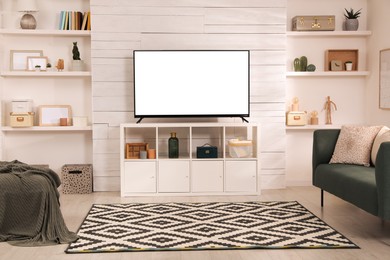 Image of Tv set with white screen on stand in room. Mockup for design