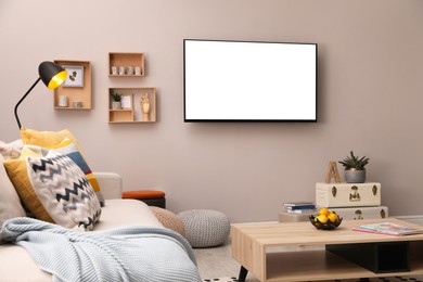 Image of Tv set with white screen mounted on wall in room. Mockup for design