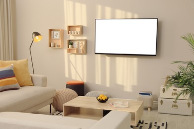 Image of Tv set with white screen mounted on wall in room. Mockup for design