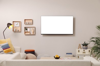 Image of Tv set with white screen mounted on wall in room. Mockup for design