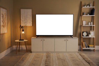 Image of Tv set with white screen on stand in room. Mockup for design